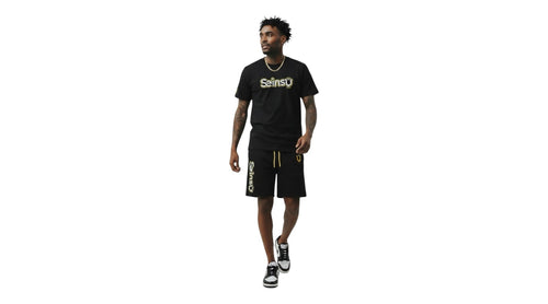 A man wearing a Seinsu Global black matching set with gold graphic t-shirt and drawstring shorts on a white background.